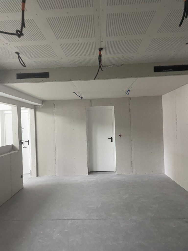 Une pièce en construction avec une porte et une fenêtre en cours d'installation.